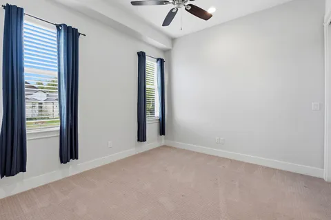 an empty room with a window and ceiling fan