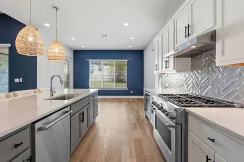 a kitchen with granite countertop a stove a sink a refrigerator and a wooden floors