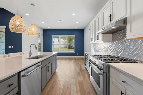 a kitchen with granite countertop a stove a sink a refrigerator and a wooden floors