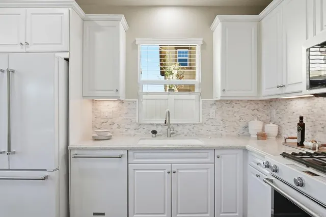 a kitchen with stainless steel appliances white cabinets and a window