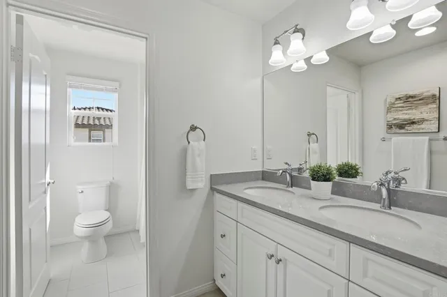 a bathroom with a granite countertop sink a toilet and a mirror