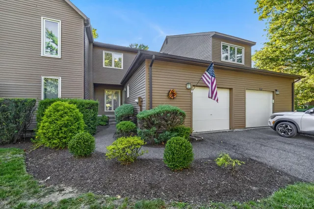 a view of a grey house with yard and plants
