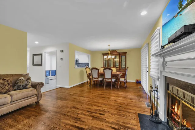 a living room with furniture a fireplace and a dining table with wooden floor