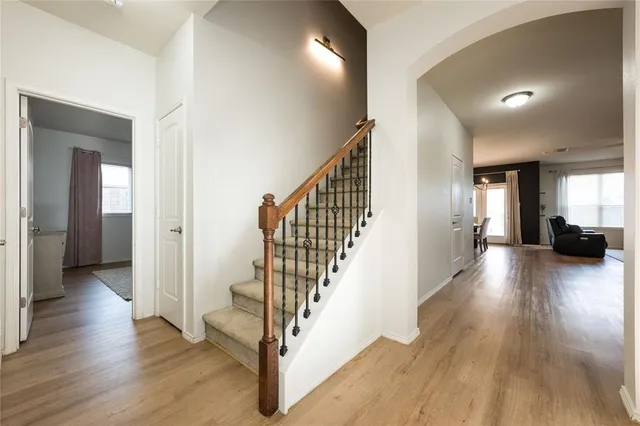 a view of a hallway with wooden floor stairs and a living room