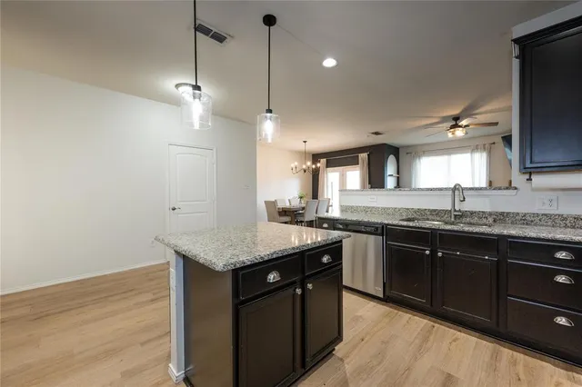 a kitchen with kitchen island granite countertop a sink a counter top space stainless steel appliances and cabinets