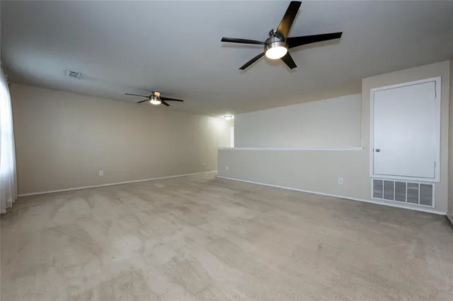an empty room with ceiling fan and window