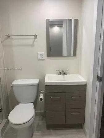 a bathroom with a toilet sink vanity and mirror