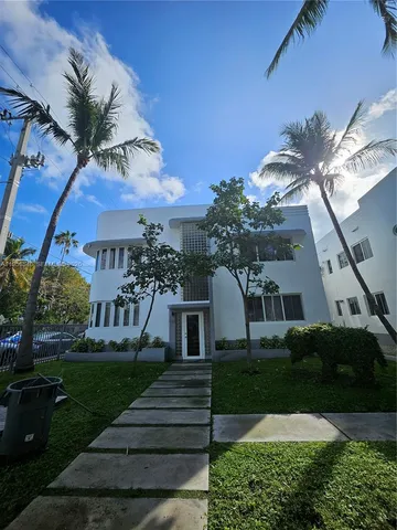 a front view of a house with a yard and potted plants