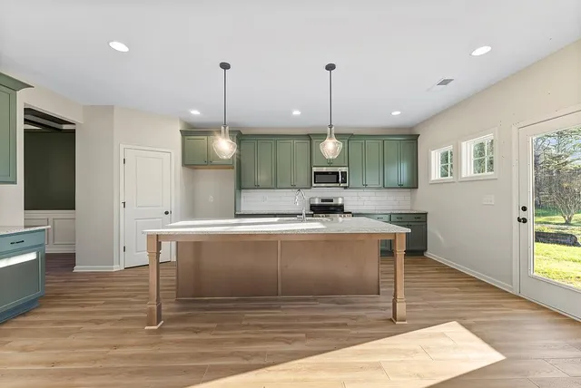 a view of a kitchen with kitchen island a sink wooden floor and a living room view