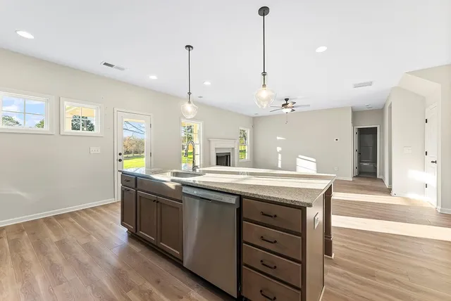 a kitchen with stainless steel appliances granite countertop a sink a stove and a wooden floor