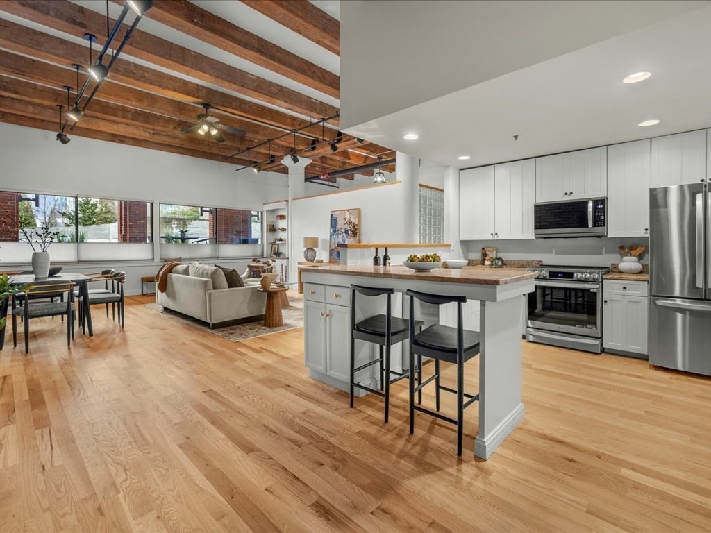 33 Sleeper Street, Unit 104 Boston, MA 02210 - Photo 2 of 23 a open kitchen with stainless steel appliances granite countertop a stove refrigerator and a dining table with wooden floor