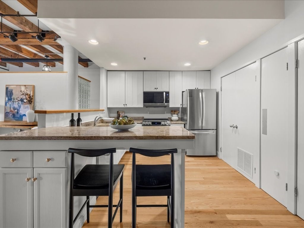 33 Sleeper Street, Unit 104 Boston, MA 02210 - Photo 10 of 23 a kitchen with stainless steel appliances granite countertop a sink a stove a refrigerator and a microwave