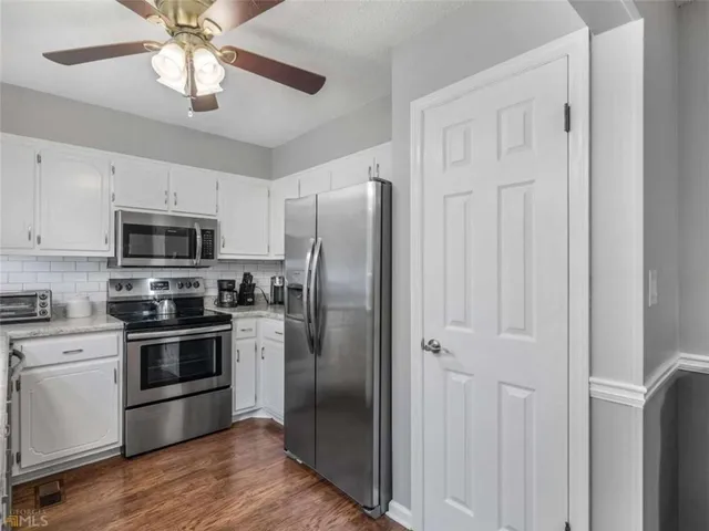 a kitchen with stainless steel appliances granite countertop white cabinets and a refrigerator