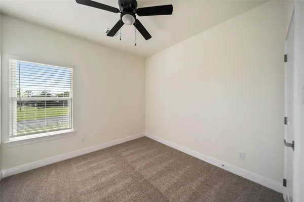 an empty room with a window and a fan