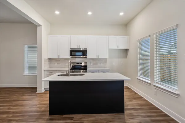 a kitchen with kitchen island a sink dishwasher a stove and a refrigerator with wooden floor