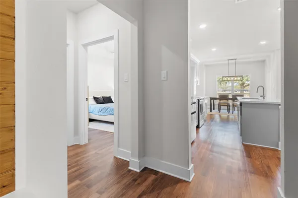 a view of a hallway with wooden floor a windows and a kitchen view