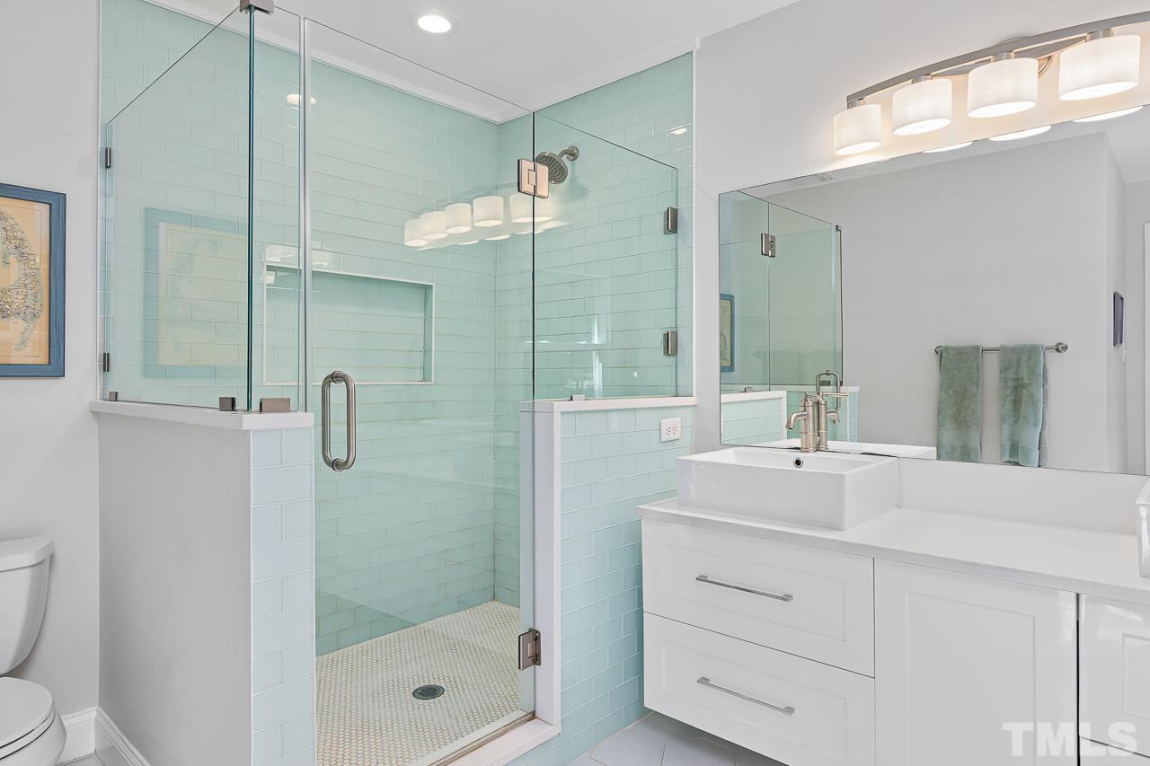 7929 Kingsland Drive Raleigh, NC 27613 - Photo 21 of 46 a bathroom with a shower sink and mirror