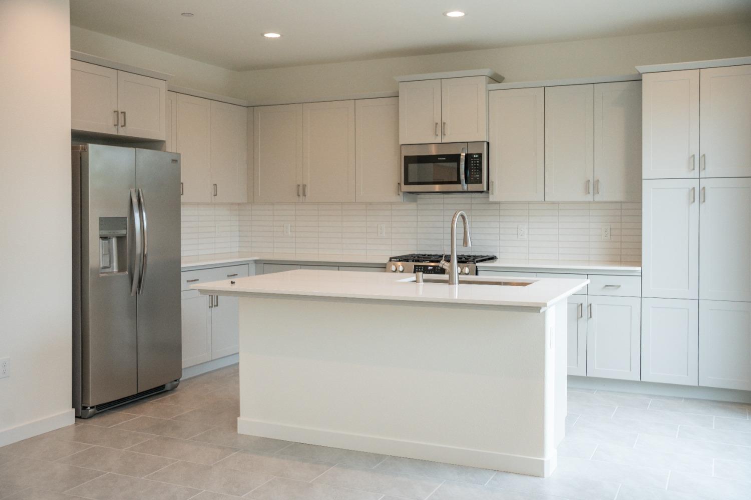 696 Philip Way Madera, CA 93636 - Photo 3 of 23 a kitchen with stainless steel appliances a sink stove refrigerator and cabinets