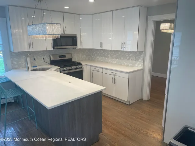 a kitchen with a sink a stove a refrigerator and white cabinets