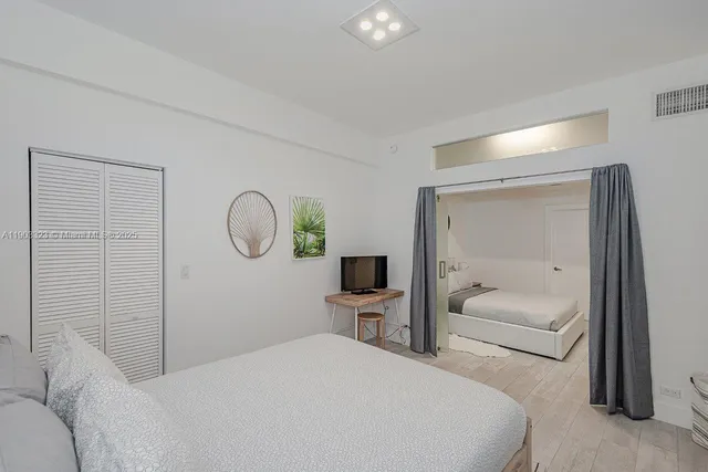 a bedroom with a bed a mirror and a window