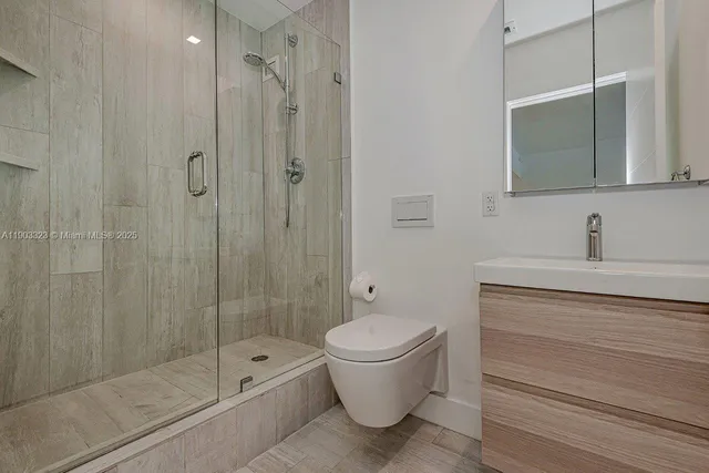 a bathroom with a shower a toilet a sink and mirror