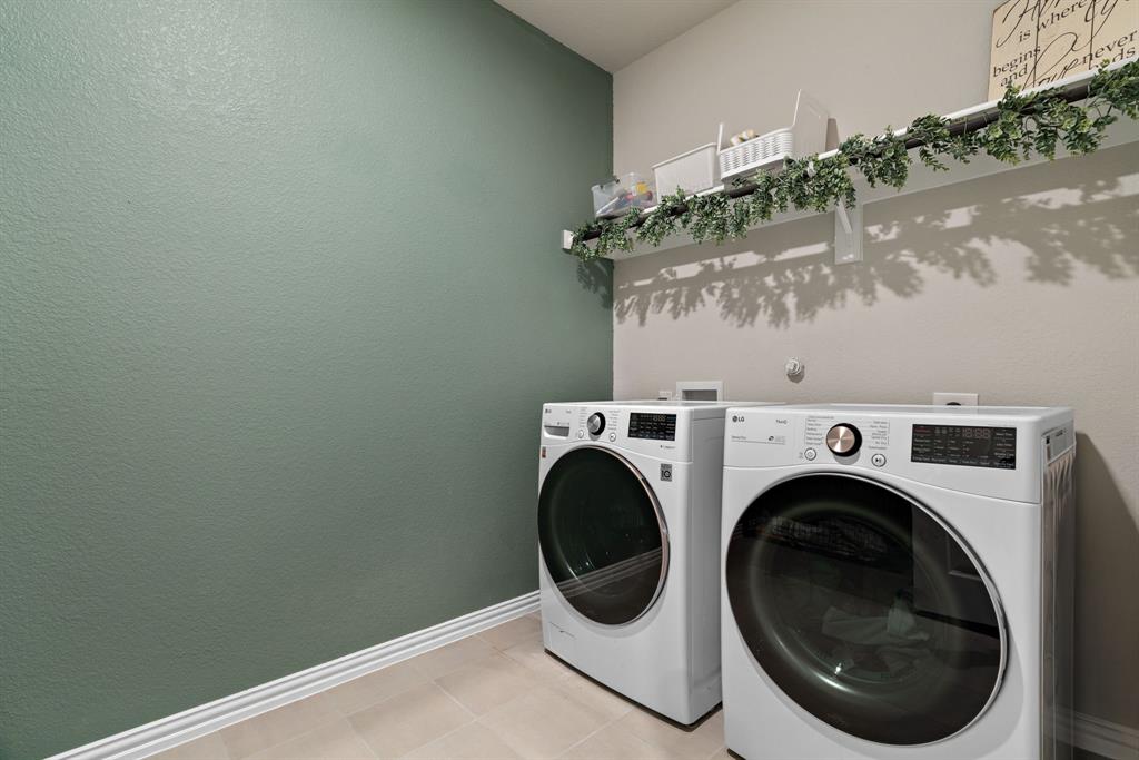 3112 Kingsgarden Road Denton, TX 76207 - Photo 32 of 38 Laundry area featuring textured green accent wall, light beige wall paint, white baseboards, and light-toned tile flooring