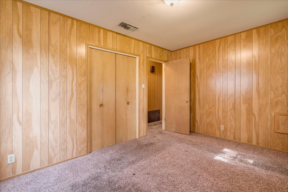 6626 Isabelle Drive Austin, TX 78752 - Photo 16 of 27 Bedroom featuring wood-finish paneling, an attached ceiling light fixture, and a built-in bi-fold door closet