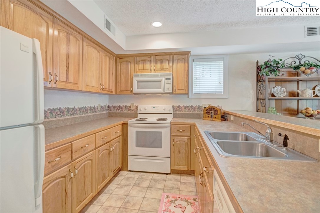 190 Still Lake Drive, Unit 321 Boone, NC 28607 - Photo 8 of 30 a kitchen with granite countertop a sink dishwasher stove and cabinets