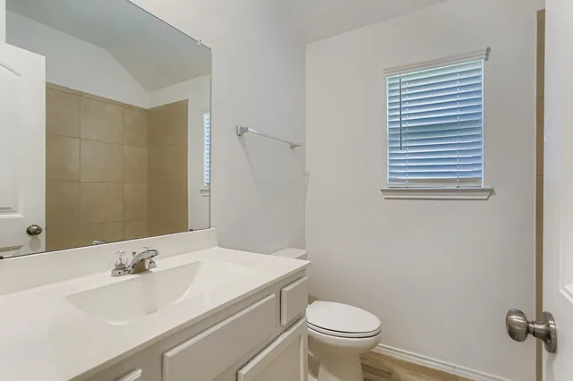 a bathroom with a granite countertop toilet a sink and a mirror