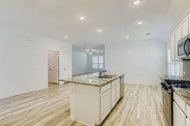 a kitchen with granite countertop sink stove and refrigerator