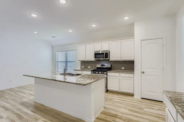 a kitchen with stainless steel appliances a sink a stove a refrigerator and cabinets