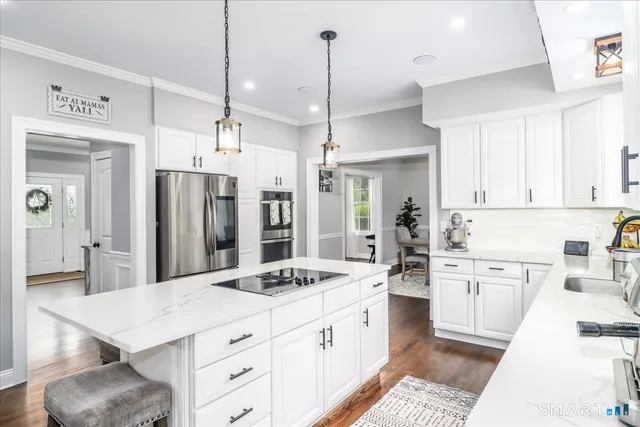 a kitchen with stainless steel appliances kitchen island granite countertop a sink refrigerator and cabinets