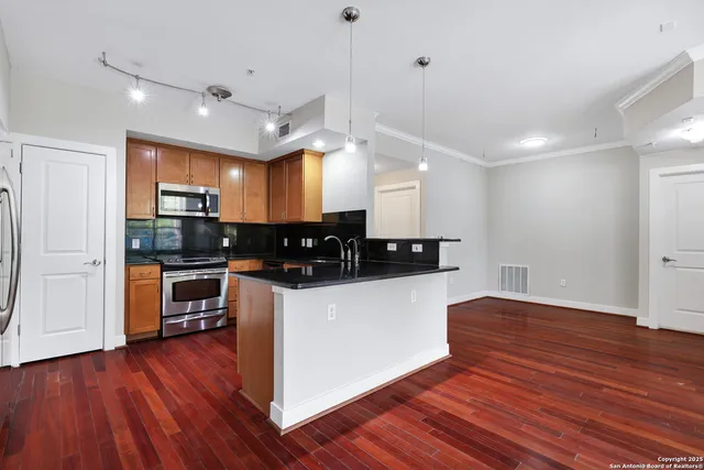 a kitchen with stainless steel appliances kitchen island granite countertop wooden floors and white cabinets