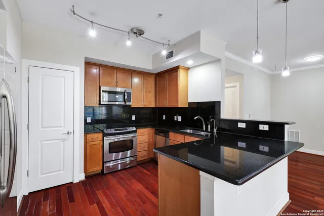 a kitchen with granite countertop a sink cabinets and stainless steel appliances