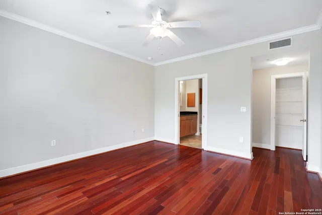 an empty room with wooden floor and a ceiling fan
