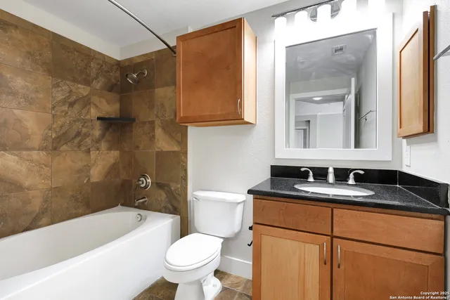 a bathroom with a granite countertop sink toilet and mirror