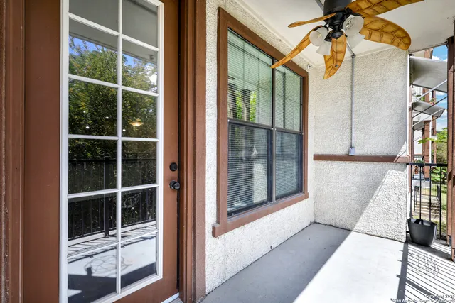 a view of a balcony with a potted plant and floor to ceiling window