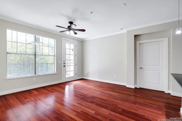 a view of an empty room with wooden floor and a window