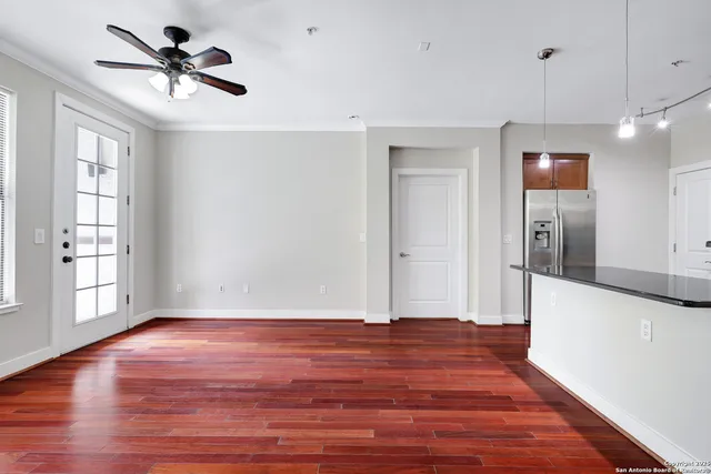 a view of empty room with wooden floor and fan