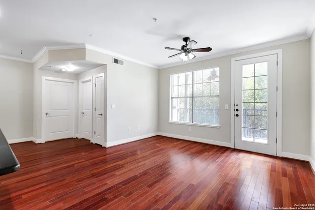a view of an empty room with wooden floor and a window