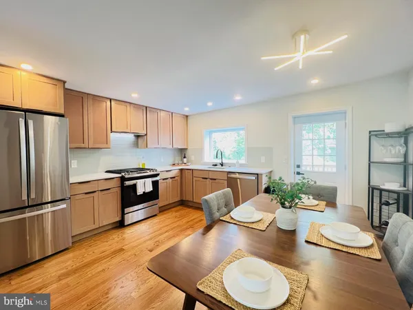 a kitchen with stainless steel appliances granite countertop a stove a sink a refrigerator dining table and chairs