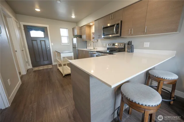 a kitchen with stainless steel appliances a stove a sink a microwave a refrigerator and cabinets