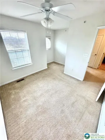 en empty room with windows and ceiling fan