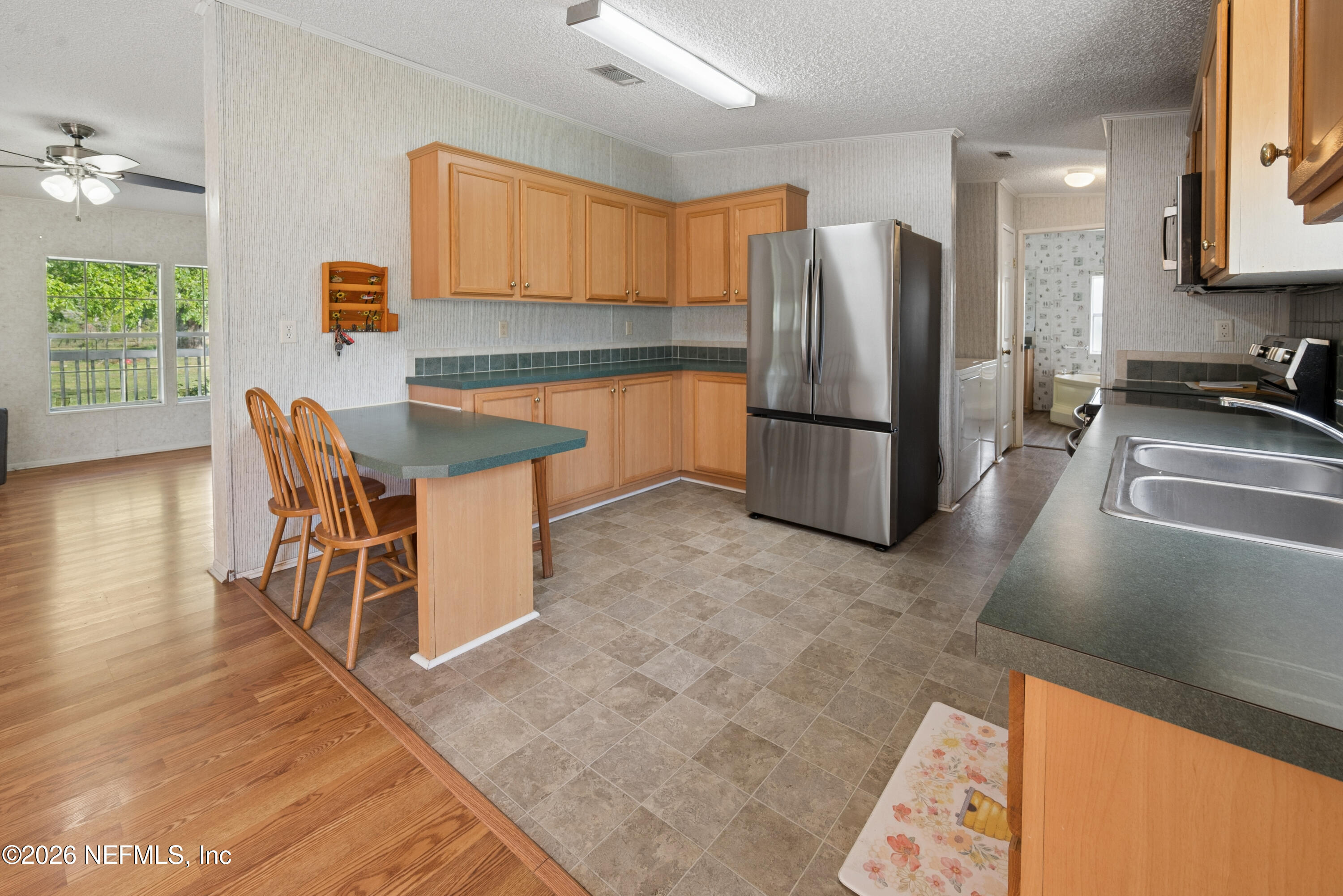 3112 Southeast 120th Street Starke, FL 32091 - Photo 9 of 30 a kitchen with stainless steel appliances granite countertop a refrigerator a stove a sink a dining table and chairs with wooden floor