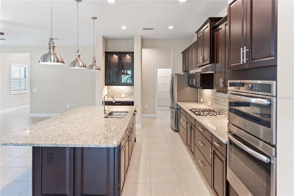 13017 Steinhatchee Loop Venice, FL 34293 - Photo 15 of 98 a large kitchen with stainless steel appliances granite countertop a stove oven and a refrigerator with wooden cabinets