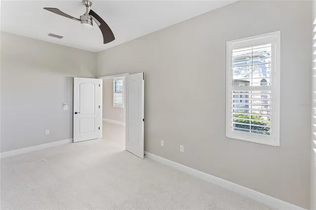 a view of empty room with floor to ceiling windows and ceiling fan