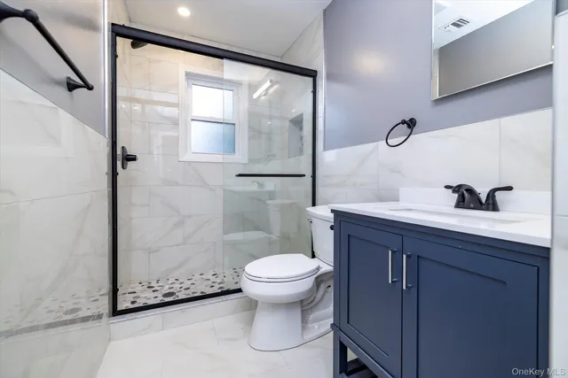 a bathroom with a granite countertop sink toilet and shower