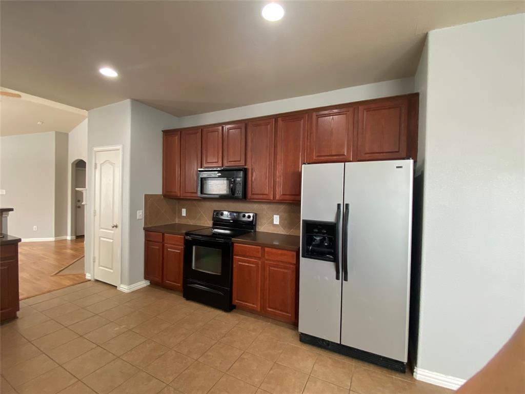 1708 Adams Place Prosper, TX 75078 - Photo 5 of 13 a kitchen with stainless steel appliances granite countertop a refrigerator and a stove top oven