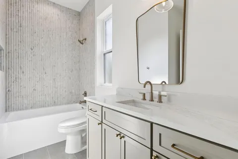 a bathroom with a granite countertop sink a toilet and a bathtub