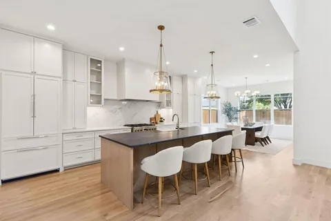 a kitchen with stainless steel appliances granite countertop a table chairs stove and white cabinets
